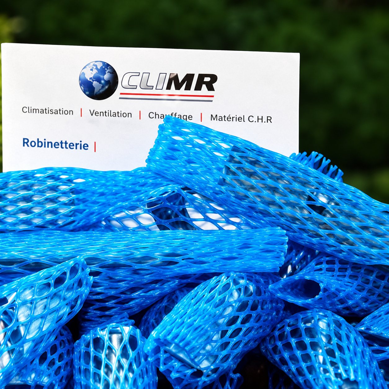 Gros plan sur un filet de protection bleu autour d'un objet, avec une étiquette blanche portant un logo et un petit texte illisible.
