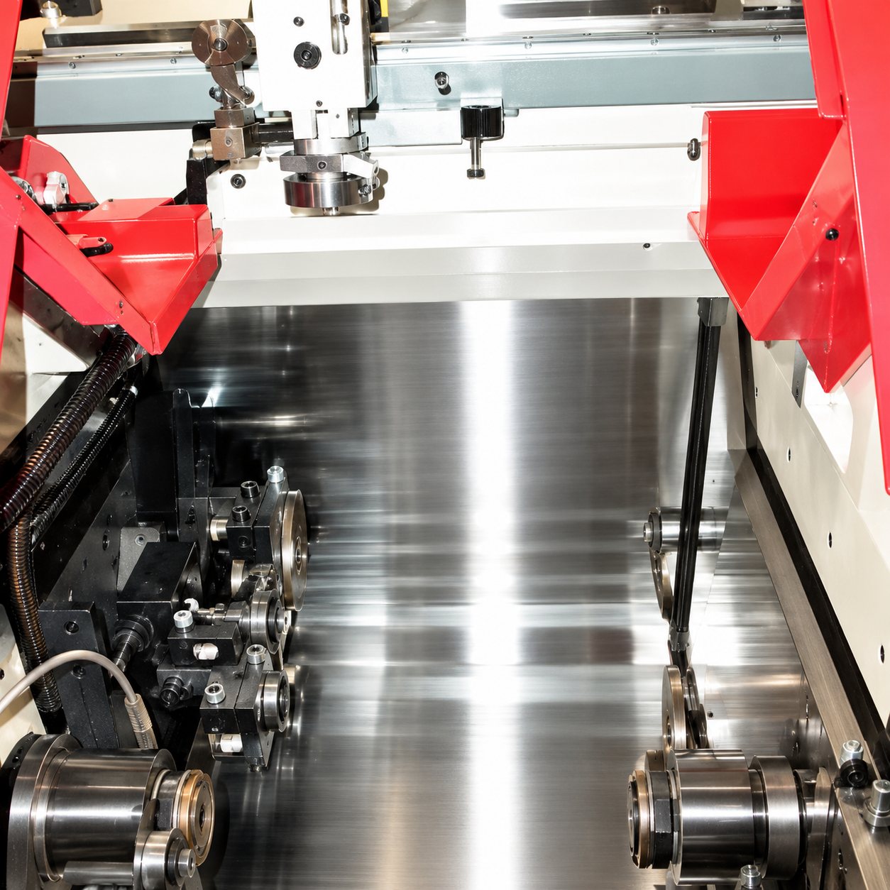 Vue rapprochée d'une machine industrielle équipée d'un plateau en acier poli et de carters rouges.